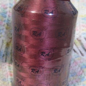 May include: A white ceramic mug with a black handle and the text "But First, Coffee" in a bold, black font. The mug is set against a blurred background, suggesting a cozy setting.