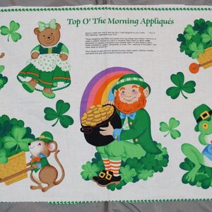 May include: A white fabric panel titled Top O' The Morning Appliques featuring printed illustrations of leprechauns holding pots of gold, bears in green dresses, frogs playing fiddles, and mice pushing wheelbarrows filled with green shamrocks.