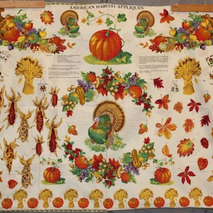 Puede incluir: Un panel de tela blanco con una variedad de aplicaciones con temática de Acción de Gracias, que incluyen una cornucopia, calabazas, maíz, hojas y un pavo. El texto "AMERICAN HARVEST APPLIQUES" está impreso en la parte superior del panel.