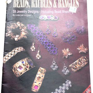 May include: A book cover with the title "Beads, Baubles & Bangles" and the subtitle "59 Jewelry Designs - Including Bead Weaving". The cover features a variety of colorful beaded jewelry designs, including bracelets, necklaces, earrings, and rings.