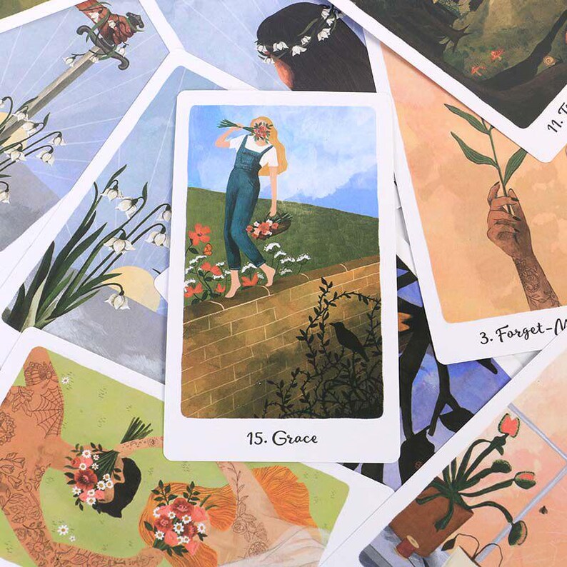 May include: A collection of tarot cards with various illustrations. One card features a woman in blue overalls carrying flowers, labeled "15. Grace." Other cards show botanical and human figures, with a sword and floral elements.
