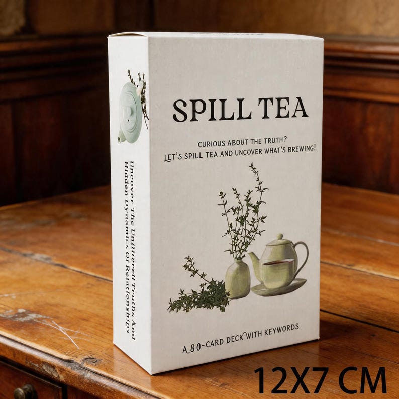 May include: A rectangular card deck box with the text "SPILL TEA" and the phrase "CURIOUS ABOUT THE TRUTH? LET'S SPILL TEA AND UNCOVER WHAT'S BREWING!". The box features illustrations of a teapot, teacup, and herbs. The dimensions are 12 x 7 cm.