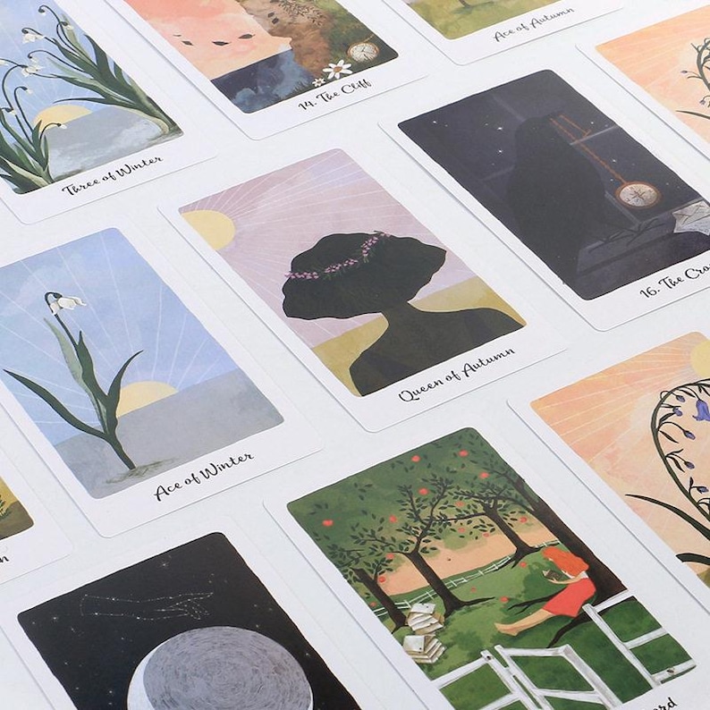 May include: A collection of tarot cards with various illustrations. The cards feature images of nature scenes, celestial bodies, and figures. Some cards have text, including "Three of Winter," "Queen of Autumn," and "Ace of Winter."