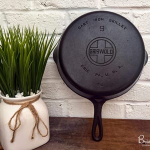 May include: A black cast iron skillet with a long handle. The bottom of the pan features embossed text reading CAST IRON SKILLET, the number 9, the Griswold logo inside a cross, and ERIE PA., U. S. A. with the number 710 at the bottom edge.