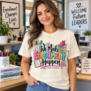 May include: A cream-coloured t-shirt featuring a colourful graphic with the text "We Make Enrollment Happen" alongside illustrations of a pencil cup, a stack of books with an apple, a clipboard, and the words "People, Process, Possibilities."