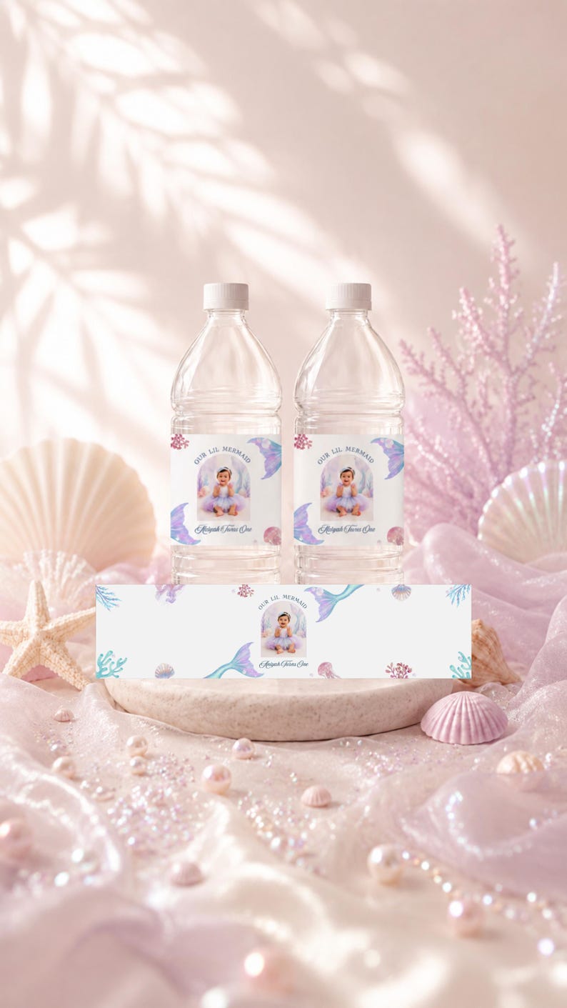 May include: Two clear plastic water bottles with white caps and custom labels featuring a photograph of a child in a mermaid costume, the text Our Lil Mermaid, and the name Aaliyah Turns One, alongside a matching horizontal label strip.