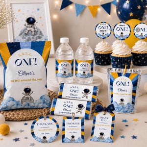 May include: A space-themed party favor set featuring a chip bag, water bottles, cupcakes with toppers, candy bars, and thank you tags. Each item displays an astronaut on a moon, blue clouds, and the text 5, 4, 3, 2, ONE! Oliver's 1st trip around the sun.
