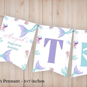 K&ouml;nnte beinhalten: Ein dekoratives Banner mit drei wei&szlig;en Wimpeln, die jeweils 12,7x17,8 cm gro&szlig; sind. Das Design zeigt Aquarellillustrationen von Meerjungfrauenschw&auml;nzen, Quallen und Korallen. Der erste Wimpel tr&auml;gt den Text Aniyah's Magical 1st Birthday.