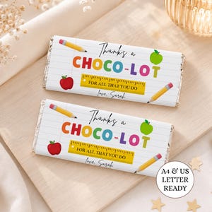 May include: Two rectangular chocolate bar wrappers featuring a white lined paper background with colorful text that reads Thanks a CHOCO-LOT FOR ALL THAT YOU DO love, Sarah. The design includes illustrations of yellow pencils, red apples, and a yellow ruler.