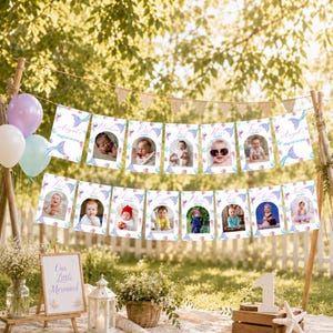 Pu&ograve; includere: Uno striscione decorativo con dodici cartoline fotografiche rettangolari con bordi a tema sirena, che mostrano le tappe mensili di un bambino. Un cartello in legno recita "Our Little Mermaid" accanto a una lanterna bianca.