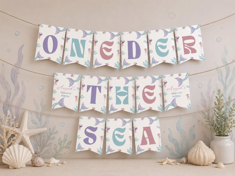 K&ouml;nnte beinhalten: Ein dekoratives Banner mit drei Reihen von Wimpeln, die an einer Schnur h&auml;ngen. Die Wimpel zeigen den Text ONEDER THE SEA in violetten, t&uuml;rkisfarbenen und rosafarbenen Buchstaben, verziert mit Illustrationen von Meerjungfrauenschw&auml;nzen und Quallen.