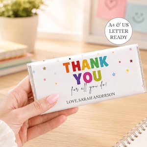 Può includere: Un incarto rettangolare per barretta di cioccolato con sfondo bianco che presenta il testo colorato THANK YOU, il testo in corsivo for all you do! e il nome LOVE, SARAH ANDERSON. Piccole stelle multicolori sono sparse sulla superficie dell'incarto.