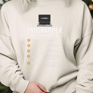 May include: Cream-coloured sweatshirt featuring the word "PROGRAMMER" in white, a laptop graphic, and hourly rate details. The design incorporates gold pound signs. A casual garment for tech professionals.