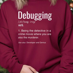 Może przedstawiać: Bordowa bluza z białym napisem "Debugging" i definicją. Definicja brzmi: "Bycie detektywem w filmie kryminalnym, w kt&oacute;rym jesteś r&oacute;wnież mordercą."