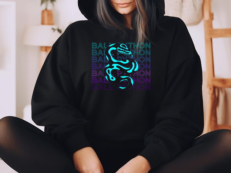K&ouml;nnte beinhalten: Schwarzer Kapuzenpullover mit einer neonblauen und violetten Schlange und dem Text "BALL PYTHON" vertikal gestapelt. Das Design ist mittig auf der Vorderseite des Kleidungsst&uuml;cks platziert.
