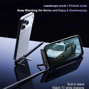 Könnte beinhalten: Ein silbernes Smartphone wird auf einem Ständer gezeigt, der ein Auto auf dem Bildschirm anzeigt. Der Ständer ist für die Anzeige im Quer- und Hochformat konzipiert. Der Text auf dem Bild lautet: "Keep Watching the Series and Enjoy It Continuously" und "Watch TV while charging."