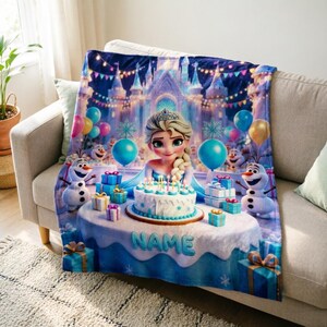 K&ouml;nnte beinhalten: Eine weiche Wohndecke mit einer farbenfrohen Illustration einer blonden Figur mit Krone, Schneem&auml;nnern und einer Geburtstagstorte auf einem Tisch. Das Motiv zeigt blaue, gelbe und rosa Luftballons, Geschenke und ein Schloss mit dem Wort NAME.