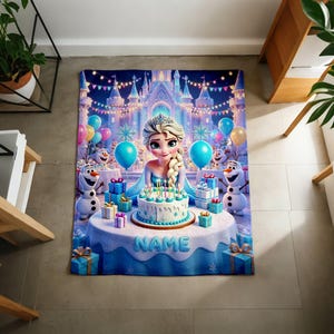 K&ouml;nnte beinhalten: Eine rechteckige Fleecedecke mit einem aufgedruckten Motiv einer blonden Figur mit Zopf, zwei Schneem&auml;nnern und einer Geburtstagstorte auf einem Tisch. Im Hintergrund ist ein Schloss mit bunten Luftballons zu sehen. Das Wort NAME steht auf dem Tisch.