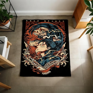 May include: A rectangular black throw blanket featuring a graphic illustration of Eren Yeager with a skeletal titan form above, a bird at the bottom, and ornate scrollwork. The text EREN YEAGER is printed in a bold font at the top of the design.
