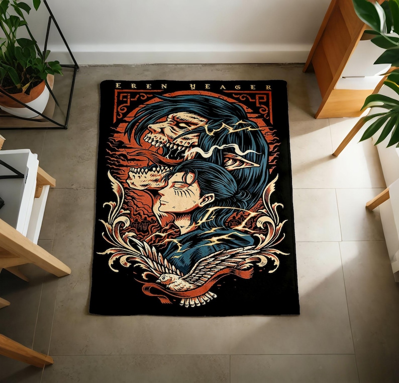 May include: A rectangular black throw blanket featuring a graphic illustration of Eren Yeager with a skeletal titan form above, a bird at the bottom, and ornate scrollwork. The text EREN YEAGER is printed in a bold font at the top of the design.
