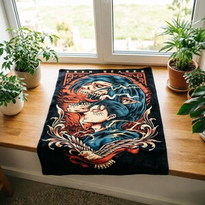 May include: A rectangular black fabric mat featuring a graphic illustration of Eren Yeager with blue hair and a skeletal titan form. The design includes orange and red accents, intricate scrollwork, and a white bird at the bottom with the text EREN YEAGER.