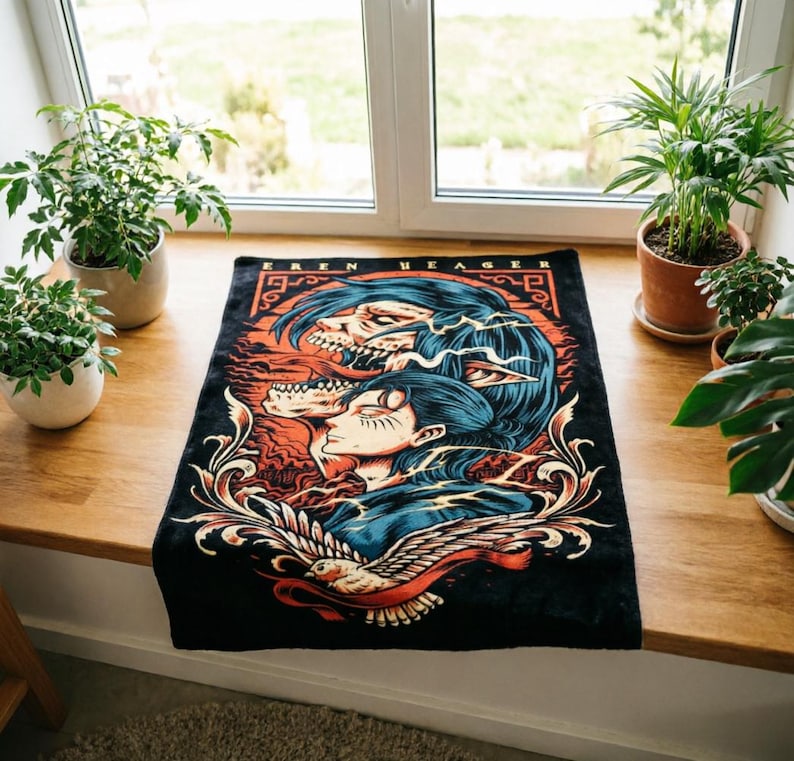 May include: A rectangular black fabric mat featuring a graphic illustration of Eren Yeager with blue hair and a skeletal titan form. The design includes orange and red accents, intricate scrollwork, and a white bird at the bottom with the text EREN YEAGER.