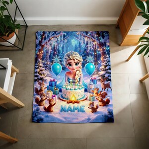 K&ouml;nnte beinhalten: Eine rechteckige Fleecedecke mit einem Zeichentrickcharakter mit blondem Zopf, einer Geburtstagstorte mit brennenden Kerzen, blauen Luftballons, Geschenken und Waldtieren in einer verschneiten Waldkulisse, wobei das Wort NAME in Blau gedruckt ist.