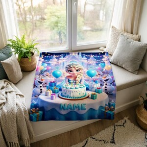 K&ouml;nnte beinhalten: Eine rechteckige Fleecedecke mit einer farbenfrohen Illustration einer blonden Figur mit Zopf, zwei Schneem&auml;nnern und einer Geburtstagstorte auf einem Tisch. Das Wort NAME ist auf die Tischdecke gedruckt, umgeben von Geschenkboxen.