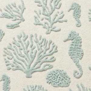 Puede incluir: Una tela textil con un patr&oacute;n repetitivo de caballitos de mar, ramas de coral y formas de coral cerebro bordadas en verde espuma de mar claro sobre un fondo blanco roto s&oacute;lido con un acabado de superficie suave y texturizado.