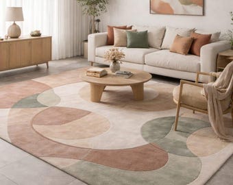 May include: A living room scene featuring a large area rug with a geometric design in shades of beige, brown, and green. The room includes a white sofa, wooden furniture, and a painting with similar color tones, creating a cohesive and stylish interior.