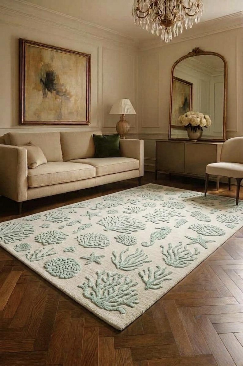 Puede incluir: Una alfombra rectangular con una base de color crema y un patr&oacute;n texturizado en relieve de vida marina en color verde menta claro, que incluye diversas formaciones de coral, estrellas de mar y caballitos de mar distribuidos por toda la superficie.