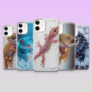 Könnte beinhalten: Eine Auswahl an Handyhüllen mit farbenfrohen Gecko-Designs. Die Hüllen zeigen Nahaufnahmen von Geckos in verschiedenen Farben, darunter Orange, Blau, Rosa und Gold. Die Geckos werden vor verschiedenen Hintergründen gezeigt, darunter eine weiße, strukturierte Oberfläche.