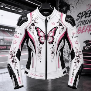 Könnte beinhalten: Eine weiß-schwarz-rosa Motorradjacke mit einem großen Schmetterlingsmotiv auf der Brust, Blumenmustern und dem Text Born to Ride, Girl Power, Speed & Beauty sowie Ride Like a Girl. Die Jacke verfügt über schwarze Schulterprotektoren.