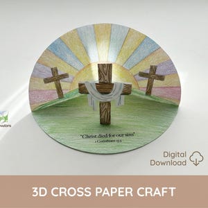 Puede incluir: Una manualidad de papel 3D circular que representa tres cruces de madera sobre una colina verde, con un colorido amanecer. La cruz central tiene un paño blanco. El texto "Cristo murió por nuestros pecados" es visible.