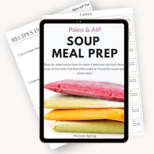 Puede incluir: Una tableta digital muestra una guía de "Paleo & AIP Soup Meal Prep" con porciones de sopa congeladas de colores. El texto incluye instrucciones para hacer y almacenar sopa. Impresiones de recetas y etiquetas son visibles en el fondo.