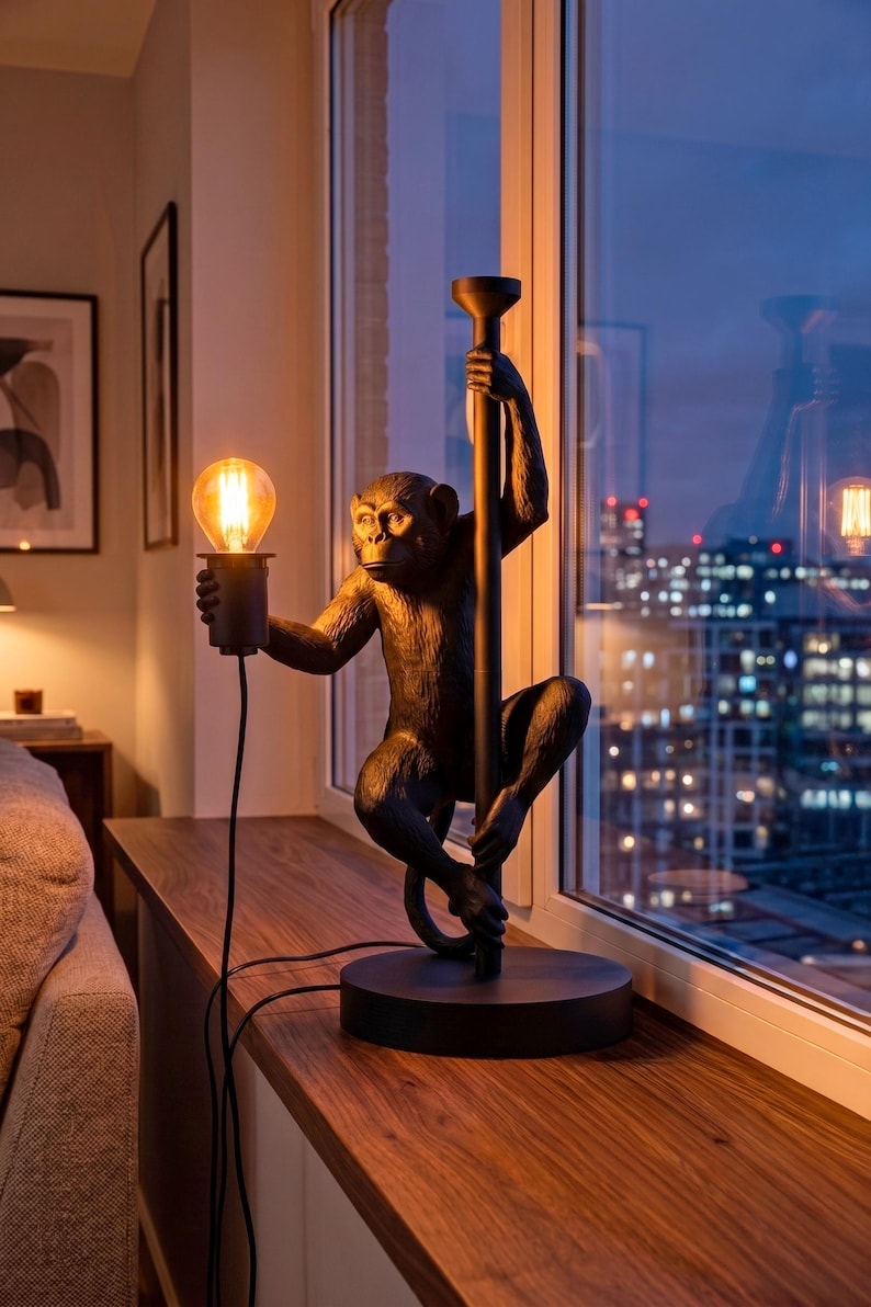 Pu&ograve; includere: Lampada da tavolo decorativa a forma di scimmia nera. La figura della scimmia tiene in mano una lampadina e si aggrappa a un palo. La lampada poggia su una base rotonda ed emette una luce calda. La lampada &egrave; alta circa 50 cm.