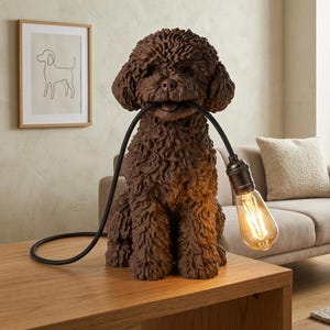 Può includere: Una lampada da tavolo a forma di cane, di colore marrone scuro e con una texture dettagliata. Il cane è seduto e tiene in bocca un cavo elettrico nero che si estende fino a una lampadina Edison in stile vintage, con un aspetto molto realistico.