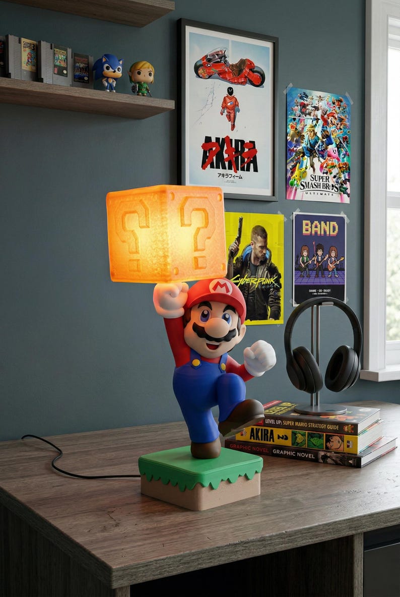 May include: A Mario-themed lamp featuring the iconic character holding a glowing question mark block. The lamp has a red hat, blue overalls, and a green base. The background includes video game posters and shelves with collectibles.