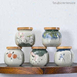 Puede incluir: Juego de tres tazas de cerámica color crema con esmalte moteado. Cada taza presenta un diseño floral pintado a mano en tonos rosa, azul y verde. Las tazas tienen una forma simple y redondeada, con un asa cómoda.