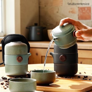 Peut inclure: Un service à thé en céramique vert et marron. L'image montre une théière versant de l'eau dans une tasse et un service à tasses empilables. L'image montre également un étui de transport noir et le texte "tsukiceramics".