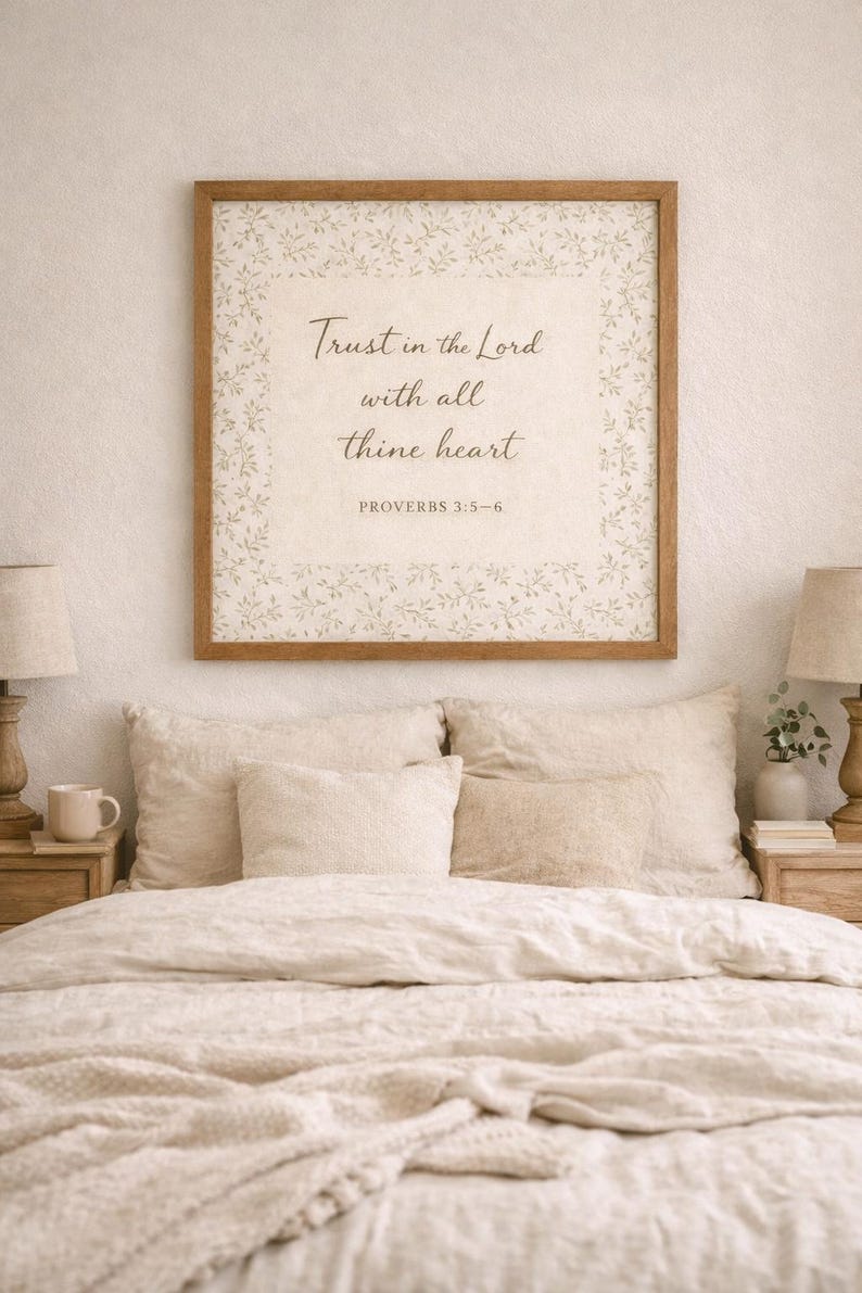 Puede incluir: Un cuadro enmarcado con el texto "Trust in the Lord with all thine heart" cuelga sobre una cama con ropa de cama beige. El marco es marr&oacute;n y el texto est&aacute; en una fuente de escritura. La cama tiene varias almohadas y dos l&aacute;mparas de noche.