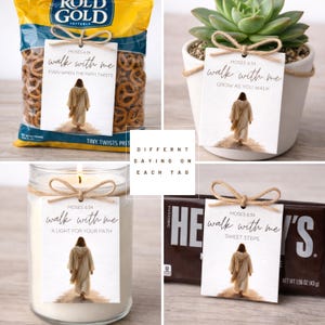 Pu&ograve; includere: Un assortimento di articoli, tra cui un sacchetto di pretzel, una pianta succulenta, una candela e una barretta di cioccolato, ciascuno adornato con un'etichetta. Le etichette presentano il testo "walk with me" e un versetto biblico, con frasi diverse.