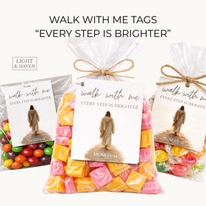 May include: Three cellophane bags filled with sweets. Each bag has a tag that reads "Walk With Me" and "Every Step is Brighter," with an illustration of a figure. The bags are tied with twine.