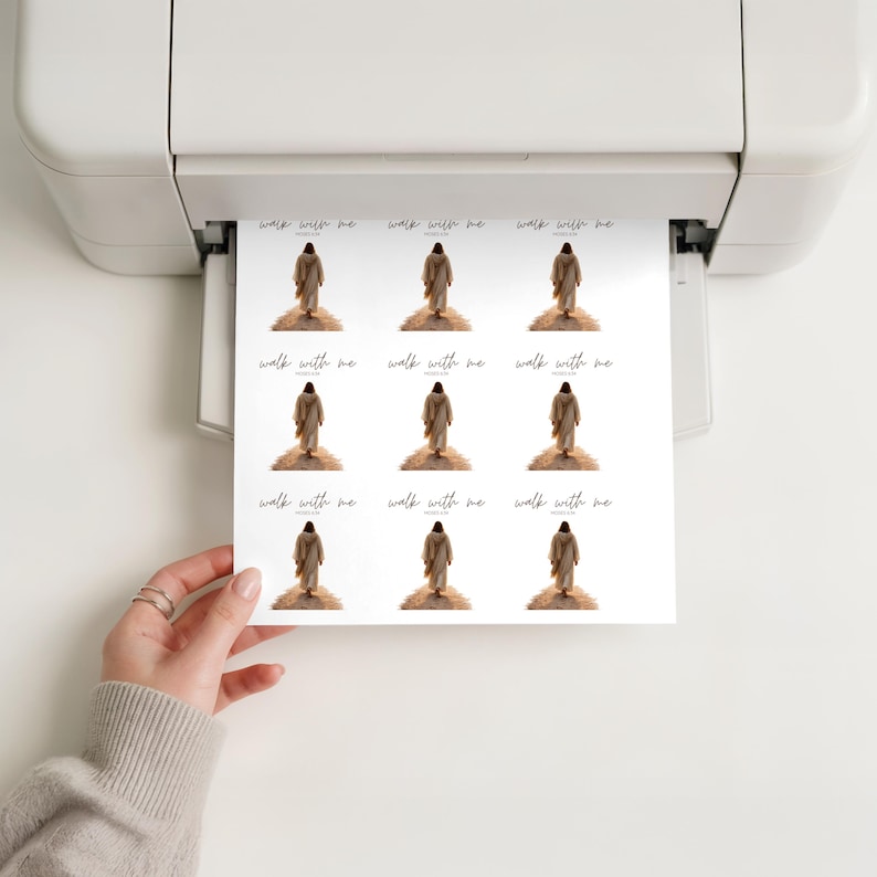 Pu&ograve; includere: Un foglio di adesivi stampati con una figura in una veste che sale una collina, con le parole "walk with me" in un carattere corsivo. Gli adesivi sono stampati su carta bianca e sono tenuti in mano.