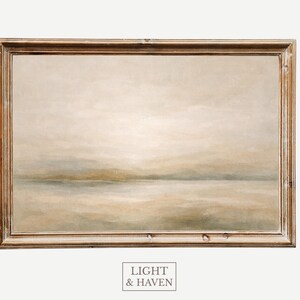 Puede incluir: Pintura de paisaje enmarcada con una paleta de colores apagados de beige, gris y marrón claro. La obra de arte representa una escena serena con una línea de horizonte suave y borrosa. El marco es de color marrón claro. El texto "LIGHT & HAVEN" está en la parte inferior.