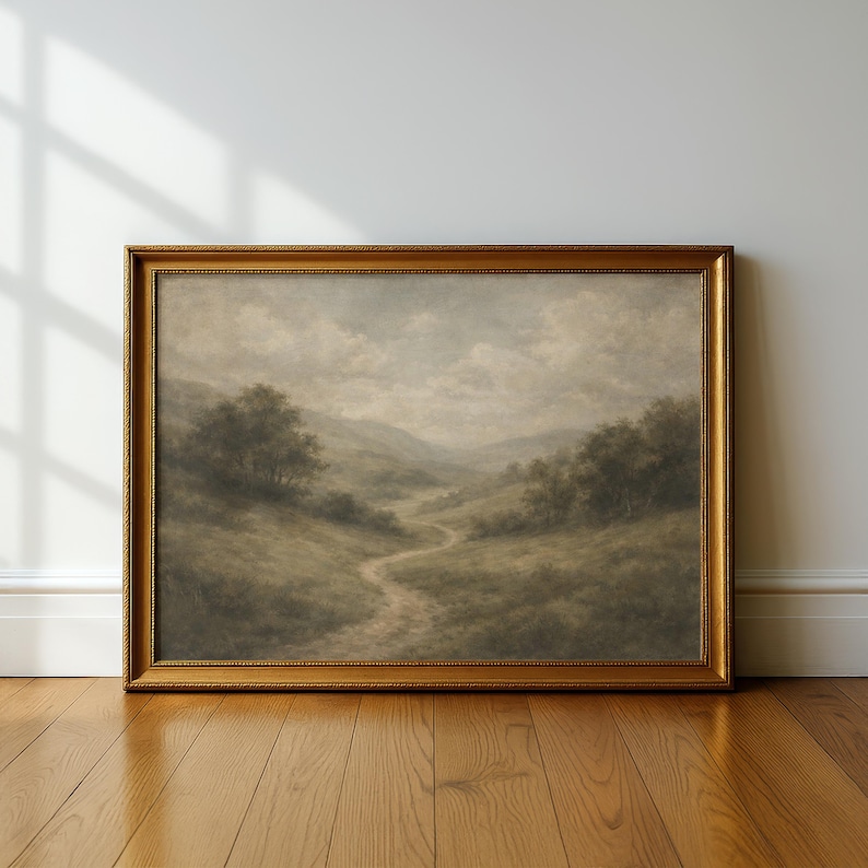 Pode incluir: Uma pintura de paisagem emoldurada com uma moldura dourada ornamentada. A obra de arte retrata um caminho sinuoso atrav&eacute;s de um vale com &aacute;rvores e colinas sob um c&eacute;u nublado. A paleta de cores &eacute; suave com tons de verde, castanho e cinza.