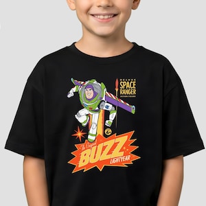 May include: Black t-shirt featuring a graphic of Buzz Lightyear in a dynamic pose, with the text "The Original Buzz Lightyear" and "Deluxe Space Ranger Action Figure". The design is in vibrant colors, including green, purple, and orange.