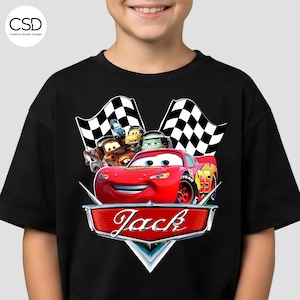 Puede incluir: Camiseta negra con un gr&aacute;fico de Rayo McQueen de la pel&iacute;cula Cars, y el nombre "Jack" en una insignia. El dise&ntilde;o incluye banderas a cuadros y otros personajes de la pel&iacute;cula.