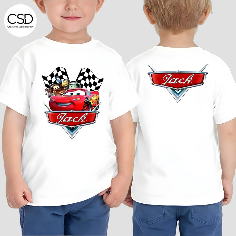 Puede incluir: Camiseta blanca con un gr&aacute;fico de coche de carreras rojo y el nombre "Jack" en la parte delantera y trasera. El dise&ntilde;o frontal incluye banderas a cuadros y coches de dibujos animados. Ropa infantil.