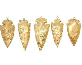 May include: Five gold-colored arrowhead pendants with a textured surface.